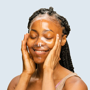 Woman applying an OmniLux Hydrogel Face Mask  with a plain background