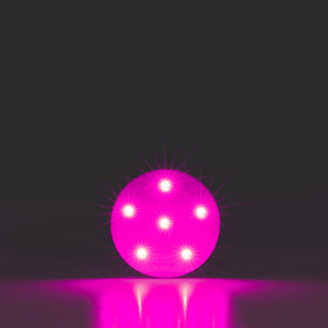 Pink glowing sphere - OmniLux Blemish Eraser- on a reflective surface with a dark background