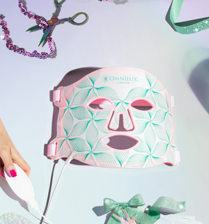 Omnilux Contour facial mask with decorative ribbons and scissors on a light blue background